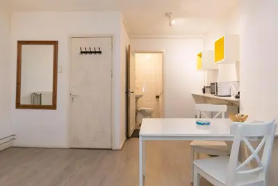 a white dining room with a table and a mirror at RedLight District Smokers Friendly Private Studio in Amsterdam