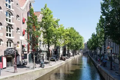 a canal in a city with buildings next to a river at RedLight District Smokers Friendly Private Studio in Amsterdam