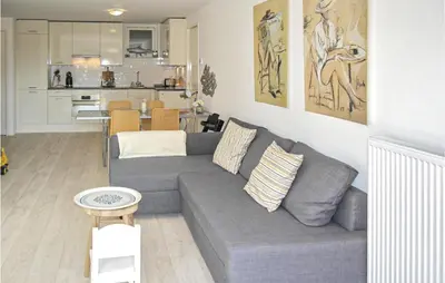 a living room with a gray couch and a kitchen at Zeekalfje in Bergen aan Zee