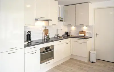 a white kitchen with white cabinets and appliances at Zeekalfje in Bergen aan Zee