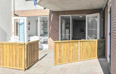 a porch with a wooden fence and sliding glass doors at Zeekalfje in Bergen aan Zee