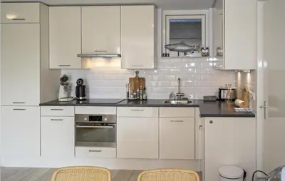 a white kitchen with white cabinets and a sink at Zeekalfje in Bergen aan Zee
