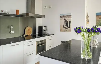 a kitchen with a vase of purple flowers on a counter at Stern in Bergen aan Zee