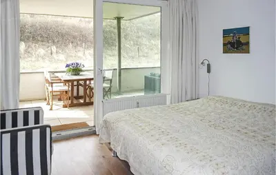 a bedroom with a bed and a balcony with a table at Stern in Bergen aan Zee