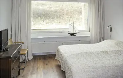 a bedroom with a bed and a window with a toy boat on the window sill at Stern in Bergen aan Zee