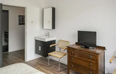 a bedroom with a dresser with a tv and a chair at Stern in Bergen aan Zee