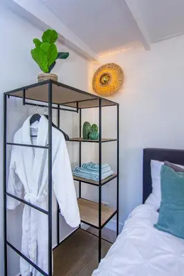 a black shelf with a white robe and a bed at Coast Guesthouse in Zandvoort
