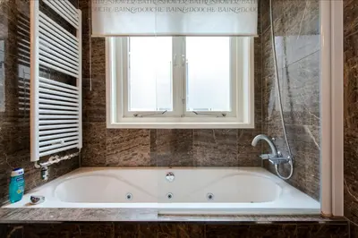 a bath tub in a bathroom with a window at B&B The Catch Apartment in Amsterdam