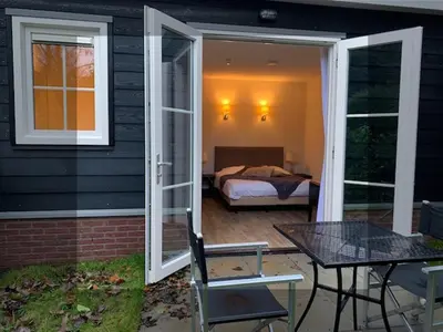 a screened in porch with a bed and a table at Herberg het Landhuis in Schoorl