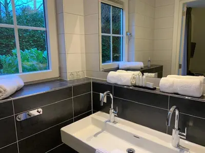 a bathroom with a sink and two mirrors at Herberg het Landhuis in Schoorl
