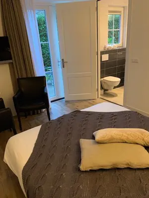 a bedroom with a bed and a bathroom at Herberg het Landhuis in Schoorl
