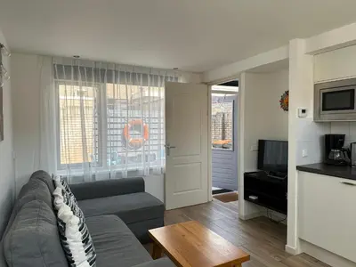 a living room with a couch and a tv at Heerlijke vakantiehuisjes in Egmond in Egmond aan Zee