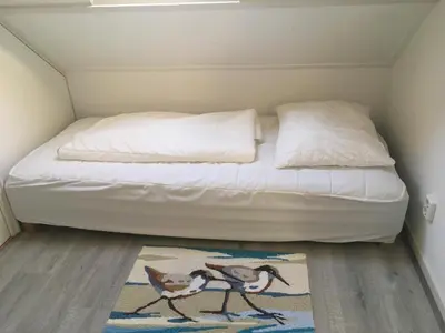 a small bedroom with a bed and a rug at Heerlijke vakantiehuisjes in Egmond in Egmond aan Zee