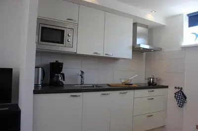 a kitchen with white cabinets and a microwave at Heerlijke vakantiehuisjes in Egmond in Egmond aan Zee