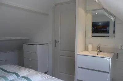 a bedroom with a bed and a sink and a mirror at Heerlijke vakantiehuisjes in Egmond in Egmond aan Zee