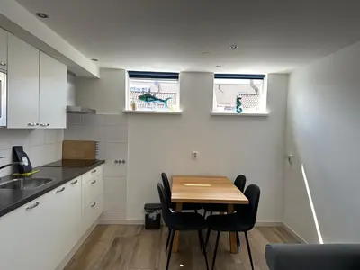 a small kitchen with a wooden table and chairs at Heerlijke vakantiehuisjes in Egmond in Egmond aan Zee