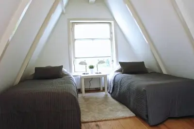 two beds in a attic room with a window at Stylish Canalhouse B in Amsterdam