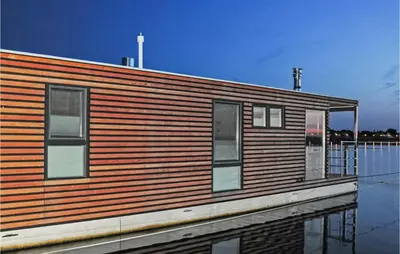 a wooden building on a body of water at Mermaid-Hausboote 2 in Lelystad