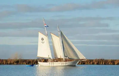 a boat with white sails on a body of water at Mermaid-Hausboote 2 in Lelystad