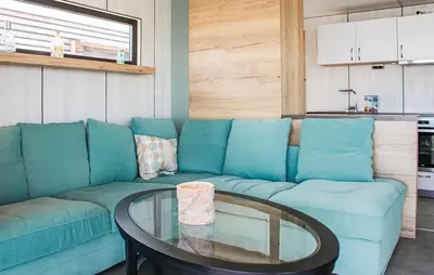 a living room with a blue couch and a glass table at Mermaid-Hausboote 2 in Lelystad