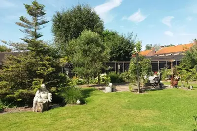 a garden with a statue in the grass at De Oude Smederij voor 2 personen in 't Veld in De Leijen