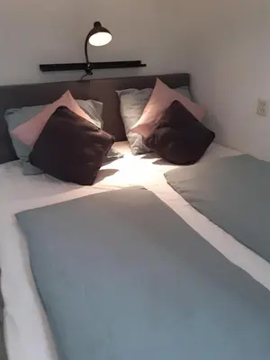 a bed with three pillows and a lamp on it at Sunny Residence in Zandvoort