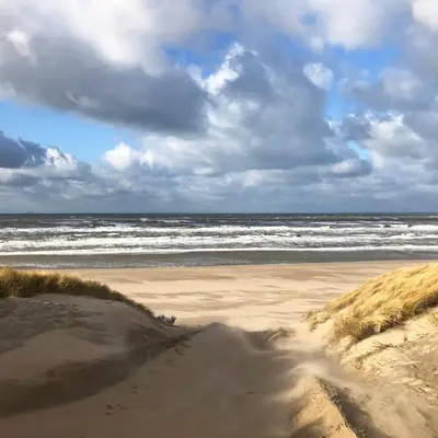 a sandy beach with the ocean on a cloudy day at Beach House For You - Luxe verblijf, 5 min van het strand in Katwijk aan Zee