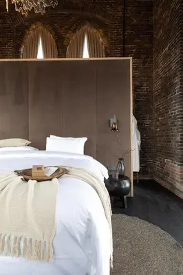 a bedroom with a white bed and a brick wall at The Clock Tower in Weesp