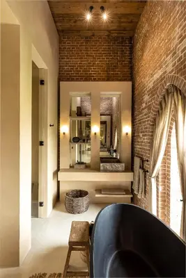 a bathroom with a black tub and a brick wall at The Clock Tower in Weesp