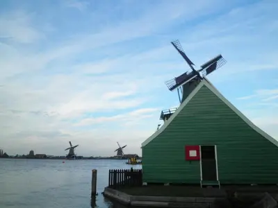 a green house with a windmill in the water at B&B HutSpot in Amsterdam