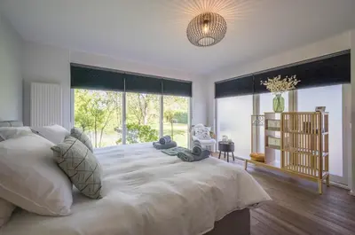a bedroom with a large white bed with a large window at 't Kleine eiland in Zuid-Scharwoude