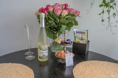 a table with a bottle of wine and a vase of flowers at 't Kleine eiland in Zuid-Scharwoude