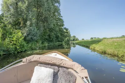 a boat with pillows on the side of a river at 't Kleine eiland in Zuid-Scharwoude