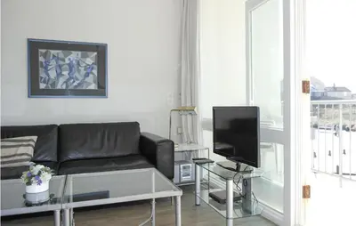 a living room with a black couch and a tv at Zeebalkon in Bergen aan Zee