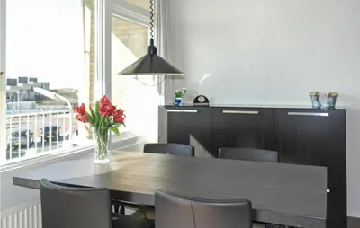 a dining room table with chairs and a vase of flowers at Zeebalkon in Bergen aan Zee