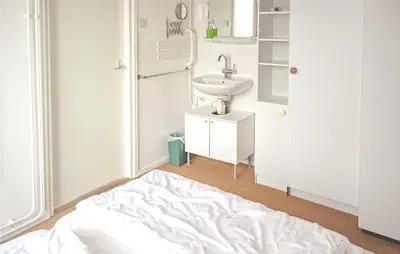 a white bathroom with a sink and a bed at Pimpernel1 in Bergen aan Zee