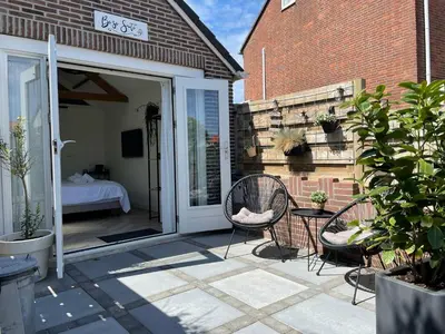 a patio with two chairs and a table and a bed at Be So Suite in Zandvoort