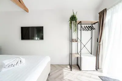 a white bedroom with a bed and a tv at Be So Suite in Zandvoort