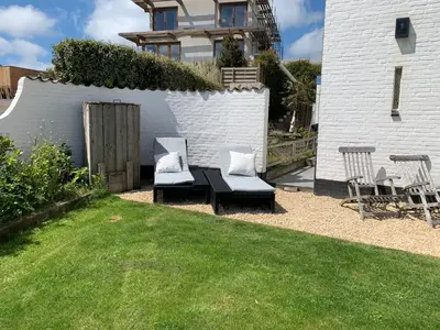 a backyard with a table and chairs and a fence at Family Villa behind the Beach in Zandvoort