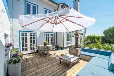 a patio with a table and an umbrella on a deck at Family Villa behind the Beach in Zandvoort