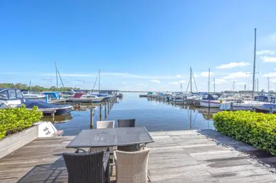 a table and chairs on a dock with boats in the water at Meerzicht 20 - Waanzinnig uitzicht over het water! in Uitgeest