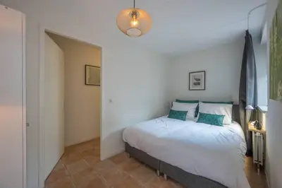 a bedroom with a white bed with blue pillows at Meerzicht 20 - Waanzinnig uitzicht over het water! in Uitgeest