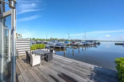 a dock with a table and chairs and boats in the water at Meerzicht 20 - Waanzinnig uitzicht over het water! in Uitgeest