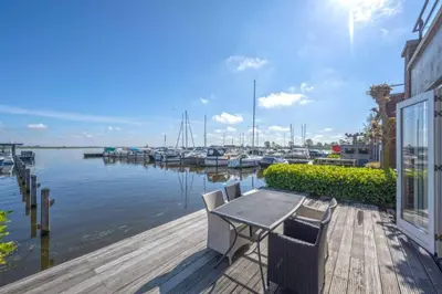 a table and chairs on a dock with boats in the water at Meerzicht 20 - Waanzinnig uitzicht over het water! in Uitgeest