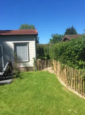 a fence in front of a house with a yard at Klein geluk in Warmenhuizen