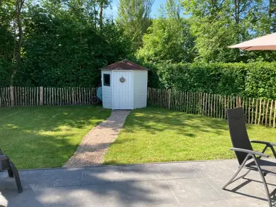 a backyard with a dog house in the grass at Klein geluk in Warmenhuizen
