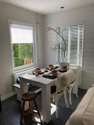 a white dining room with a table and chairs at Klein geluk in Warmenhuizen