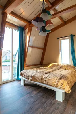 a bedroom with a bed in a room with windows at klein polderhuis - bollenschuur in Roelofarendsveen
