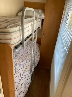 a bunk bed in a small room with a window at Chalet Ibiza in de duinen van IJmuiden aan Zee in IJmuiden