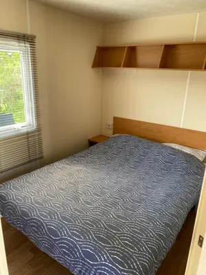 a small bedroom with a bed and a window at Chalet Formentera in de duinen van IJmuiden aan Zee in IJmuiden